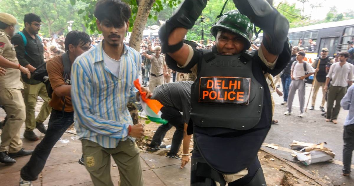 Un ofițer de poliție din Delhi folosește un baston în timp ce un protestatar trece în fugă pe lângă el în timpul unei acțiuni împotriva demonstranților, în timpul protestelor organizate de Partidul Cockroach.
