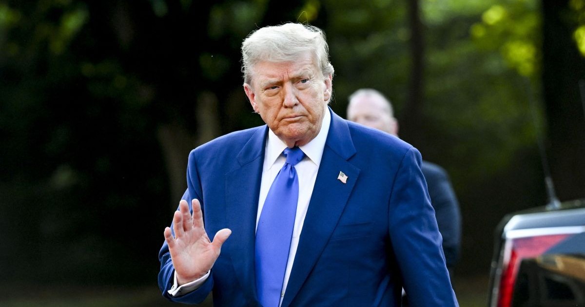 Donald Trump, îmbrăcat în costum albastru și cu o insingnă cu steagul SUA la rever, face cu mâna în timp ce sosește la summitul NATO de la Haga, Țările de Jos, 25 iunie 2025