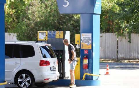 Un bărbat care se uită la ecranul unei pompe dintr-o stație de carburanți, lângă un autoturism alb Volkswagen parcat pentru alimentare. Foto: Libertatea/ Dumitru Angelescu