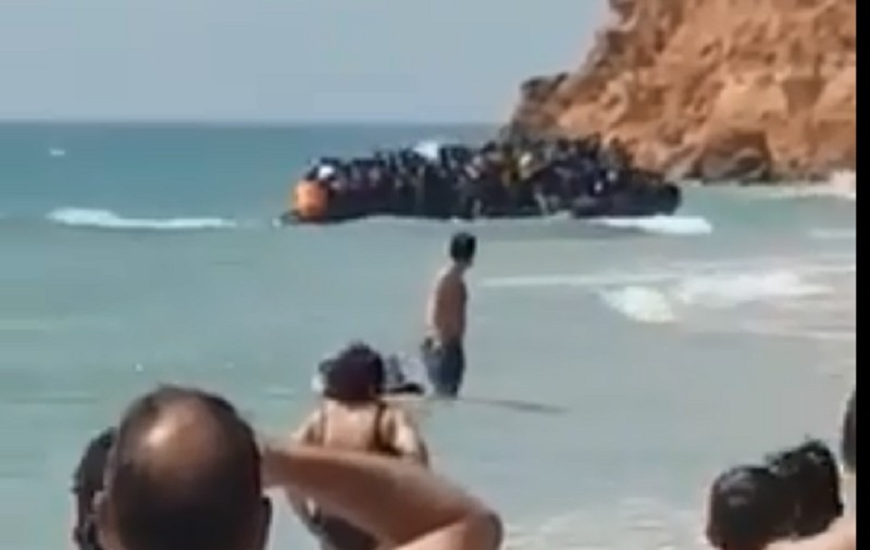 VIDEO / Momentul în care o barcă cu zeci de migranți ajunge pe o plajă de lux plină cu turiști