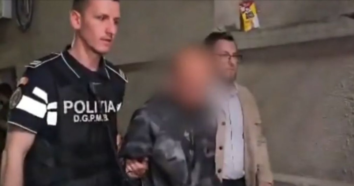 Un bărbat care are fața blurată și este escortat la Secția de Poliție de către doi agenți
