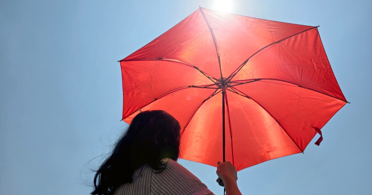 O femeie care ține o umbrelă roșie în ploaie
