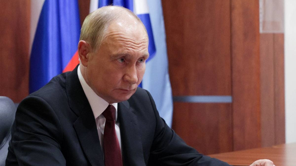 În imagine președintele Rusiei, Vladimir Putin, îmbrăcat în costum, așezat la birou, privește încruntat