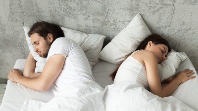 Unhappy indifferent couple sleeping separately back to back in b