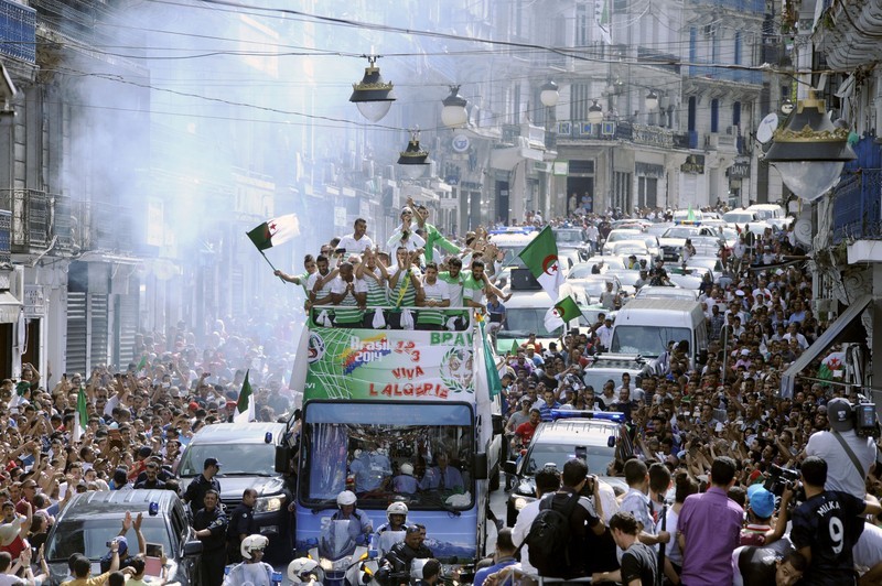 epa04296043 Algerian national soccer team players (atop bus) are welcomed by soccer fans after their return from the FIFA World Cup, in Algiers, Algeria, 02 July 2014. Algeria lost their FIFA World Cup 2014 round of 16 soccer match against Germany 1-2 in extra-time on 30 June. EPA/STR