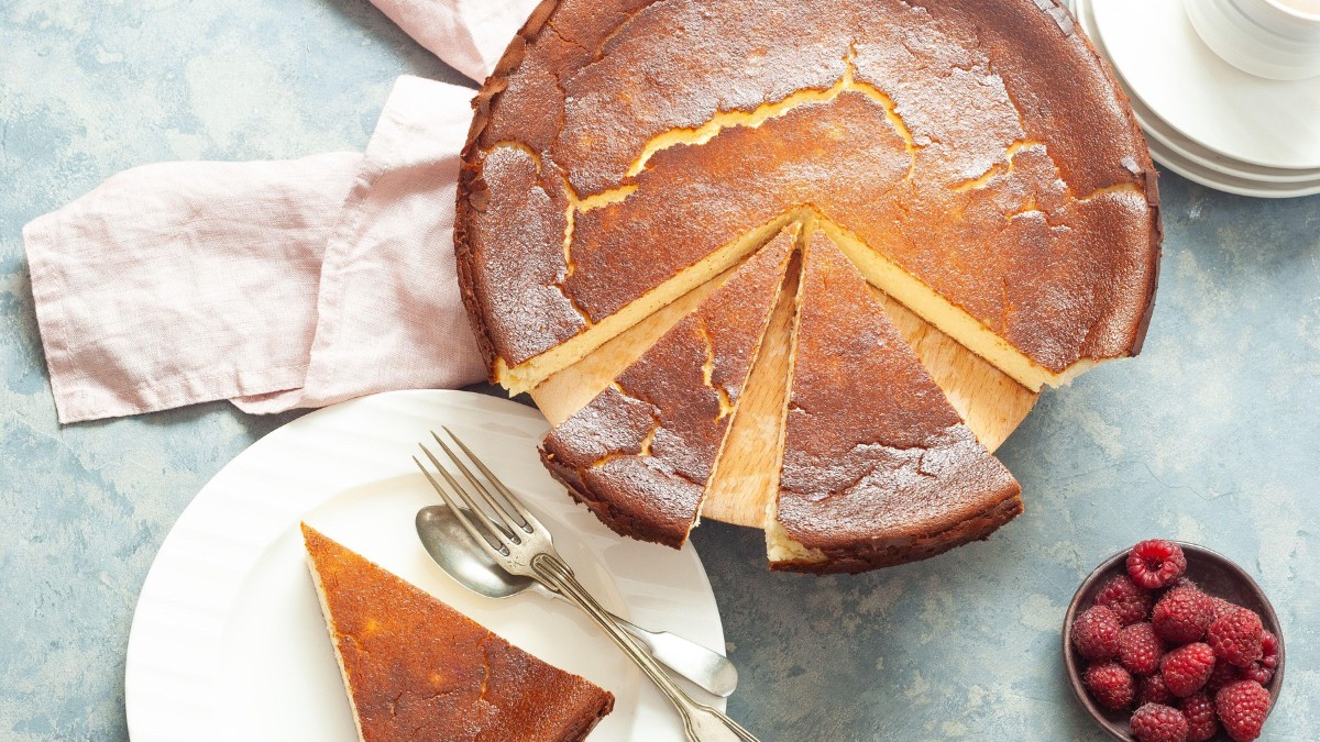 o farfurie alba cu desertul San Sebastian Cheesecake și un castron de zmeură lângă