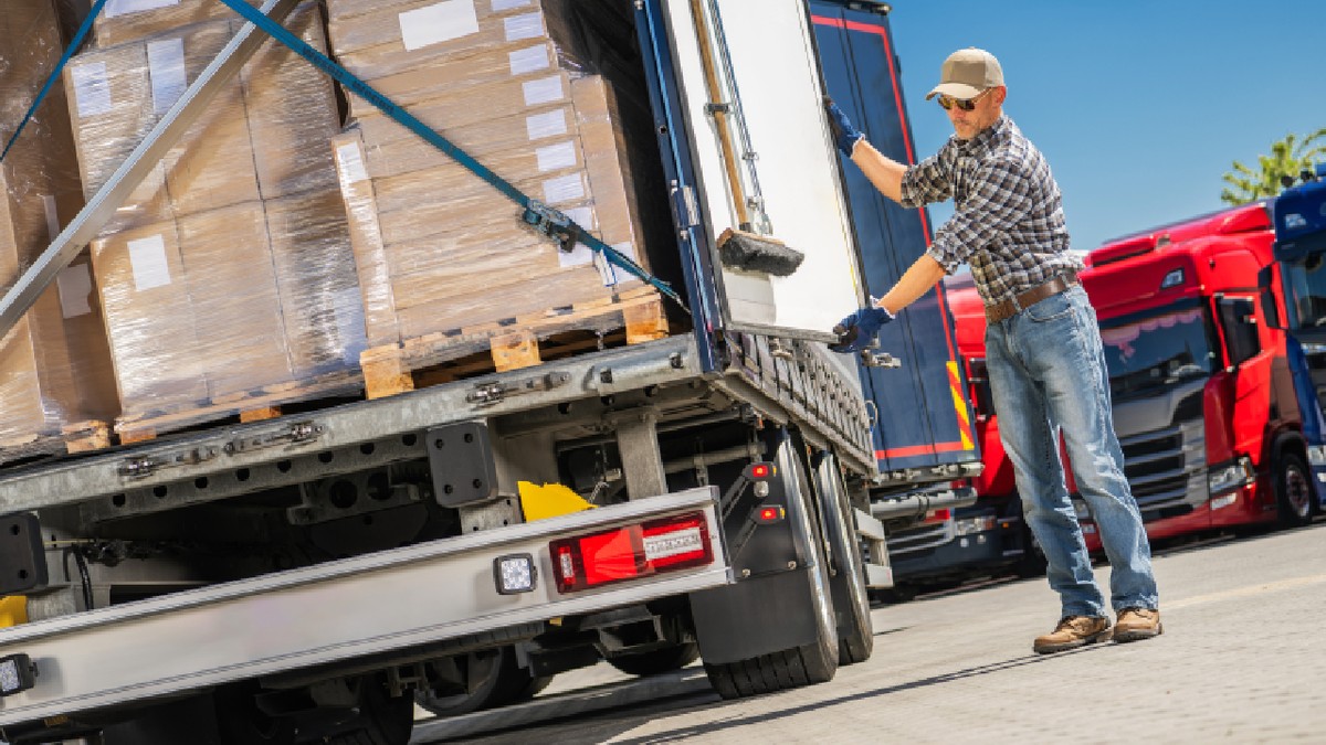 Un șofer de camion încarcă cutii cu marfă într-un camion comercial