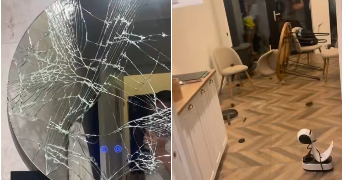 În stânga este o oglindă de la baie, spartă. În dreapta sunt scaune căzute pe jos și mai multe obiecte aruncate pe podea.