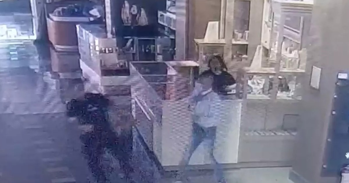 Imagine de pe o camera de supraveghere dintr-un magazin de bijuterii. În stânga, un bărbat care fuge, în dreapta o femeie, vânzătoarea magazinului