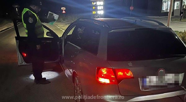 Un polițist de frontieră verifică actele unui șofer, noaptea, usa soferului este deschisă