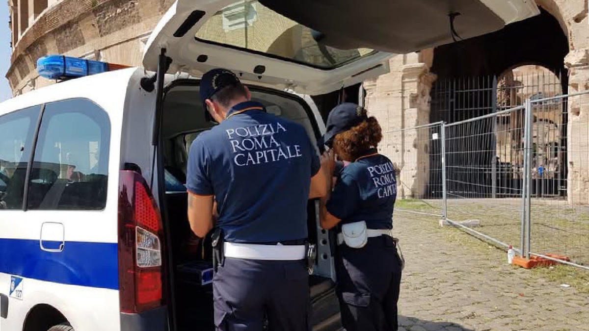 Doi agenti ai Poliției Locale Roma langa o masina de politie parcata langa Colosseum
