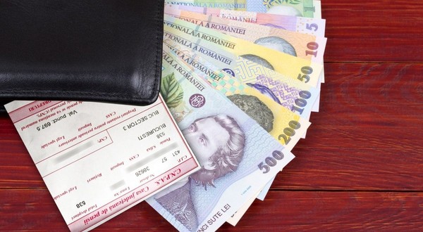 Mai multe bancnote românești ies dintr-un portofel al cărui colț negru se vede pe o masă, iar deasupra banilor este un cupon de pensie
