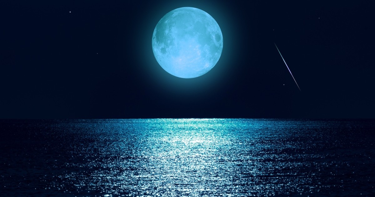 Luna plină din 30 august, o Superlună Albastră în zodia Peștilor - Imagine cu o lună plină deasupra unui peisaj marin, într-o lumină cu tentă albăstruie.