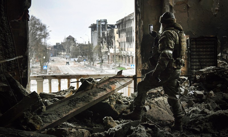 Un soldat rus patrulează in teatrul dramatic din Mariupol, bombardat pe 16 martie, pe 12 aprilie 2022. Foto: AFP