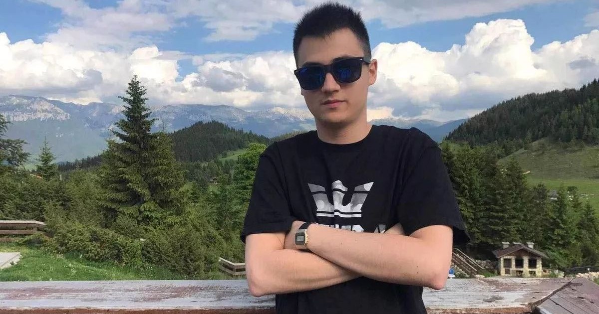 Denis Petre, fiul avocatei din București, într-un tricou negru și ochelari de soare, pe o terasă cu fundal montan