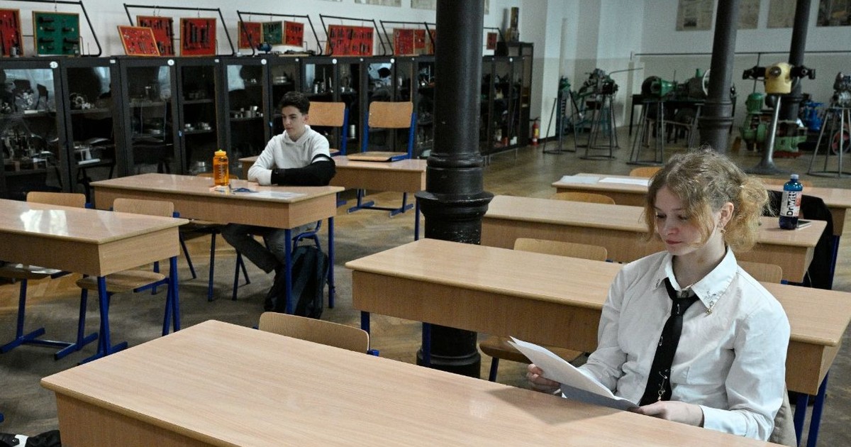 Elevă care stă în bancă la școală și citește lucrarea primită la examen