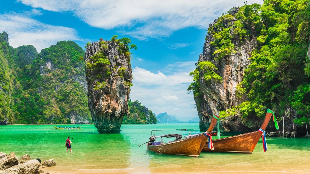 Stațiunea Phang Nga din Thailanda, un bărbat intră în apă, în timp ce alte 2 bărci sunt trase la mal