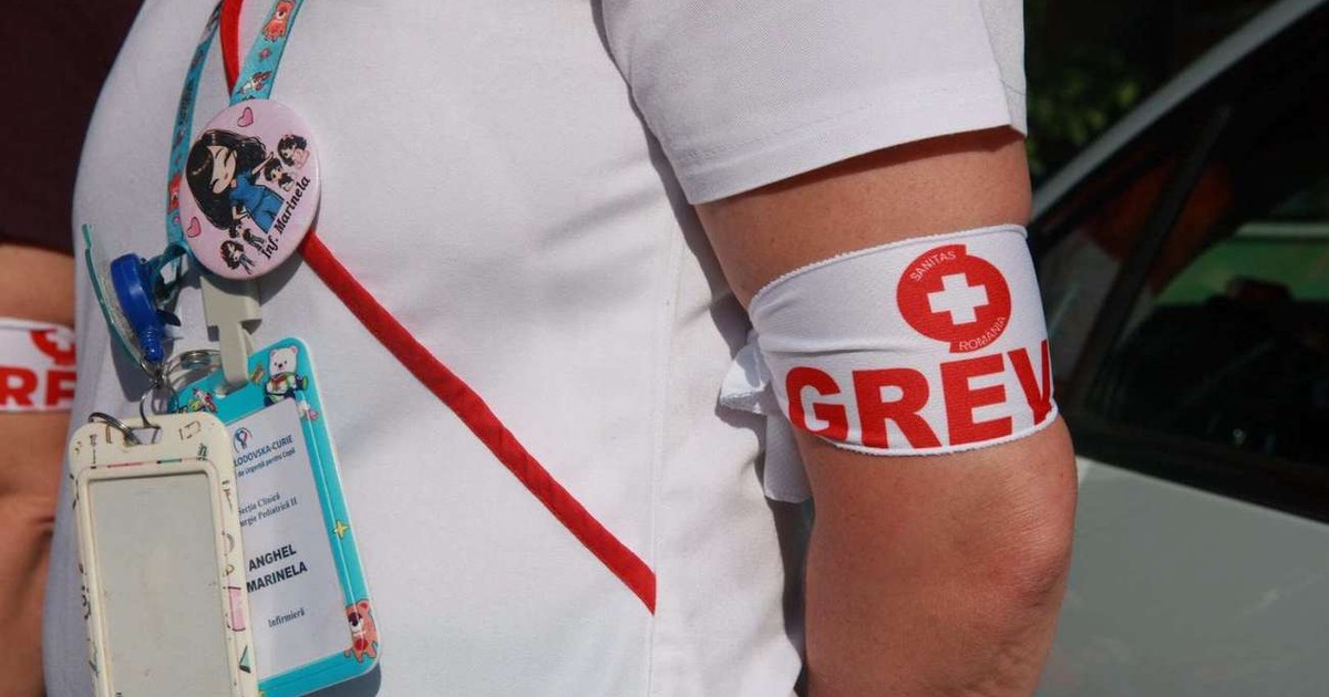 O mână a unei asistente pe care este înfăsurată o banderolă ăe scare scrie: grevă