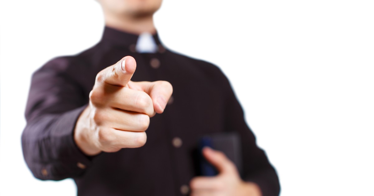 Profesor de religie care arată cu degetul amenințător