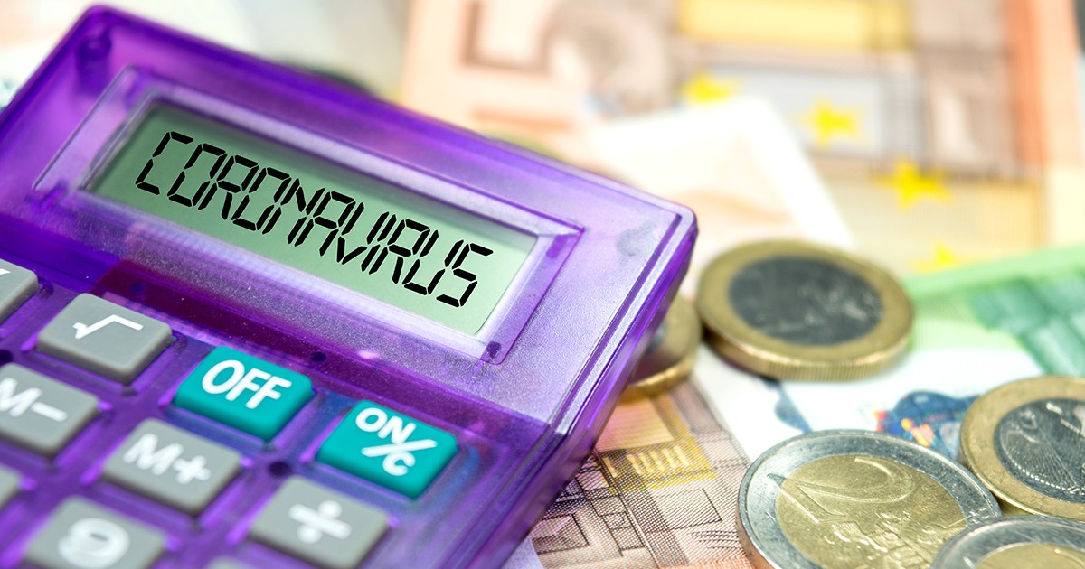 Guvernul a obținut un miliard de euro de la Comisia Europeană pentru firmele mici și mijlocii. Bancnote și monede euro pe o masă, lângă un calculator de birou pe care scrie coronavirus