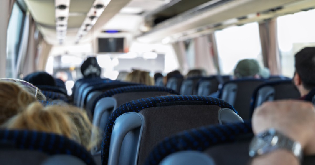 Fotografie a interiorului unui autobuz modern cu pasageri așezați. Imaginea prezintă rânduri de scaune confortabile și pasageri care se bucură de călătorie