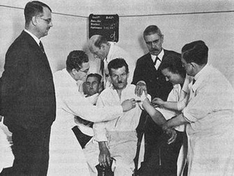 Wagner-Jauregg (centru dreapta în jachetă neagră) urmărind o transfuzie de la un pacient cu malarie (partea din spatele grupului) la o victimă a neurosifilisului (centru) în 1934. Foto: wikipedia.org
