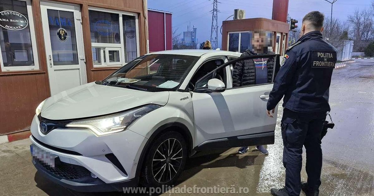 Imaginea surprinde un agent al Poliției de Frontieră efectuând un control asupra unui autoturism alb Toyota parcat în fața unui punct vamal, în prezența unei persoane a cărei identitate este protejată.