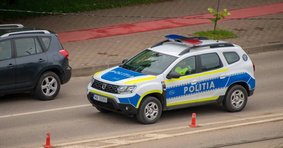 O mașină de Poliție rutieră în timp ce aleargă pe o șosea din oraș, se deplasează la locul unui accident, la volan este un polițist în uniformă