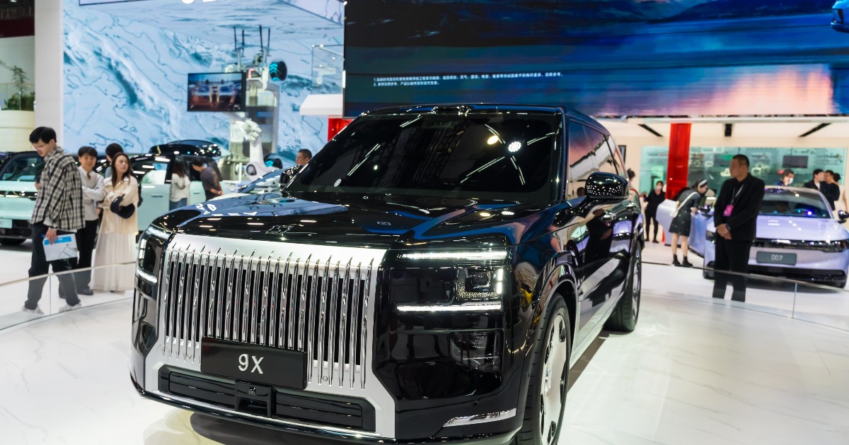 Fotografia surprinde un SUV electric de lux expus la un salon auto din China, evidențiat printr-o grilă frontală masivă și un design impunător.