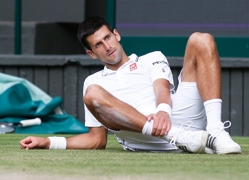 epa04302736 Novak Djokovic of Serbia takes a fall against Roger Federer of Switzerland in the men's singles final of the Wimbledon Championships at the All England Lawn Tennis Club, in London, Britain, 06 July 2014. EPA/SANG TAN / POOL