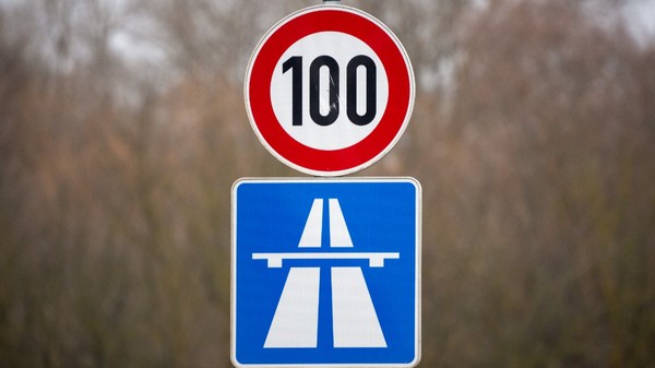 Indicator rutier de limitare a vitezei la 100 km/h, amplasat deasupra unui panou albastru care semnalizează intrarea pe o autostradă.   