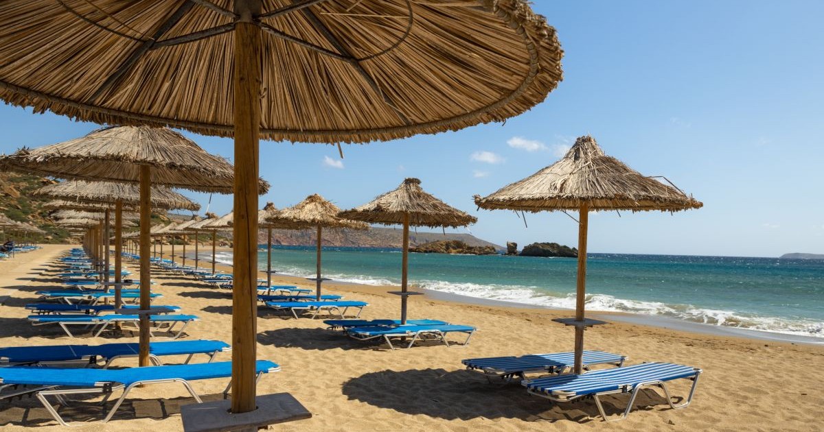 Șezlonguri și umbrele din stuf pe plaja Vai de pe insula Creta, Grecia