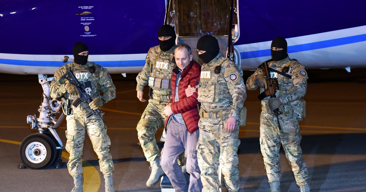 Alexander Lapshin, în centru, un blogger rus reținut de poliția din Belarus în decembrie 2016, este escortat dintr-un avion pe aeroportul din Baku, Azerbaidjan