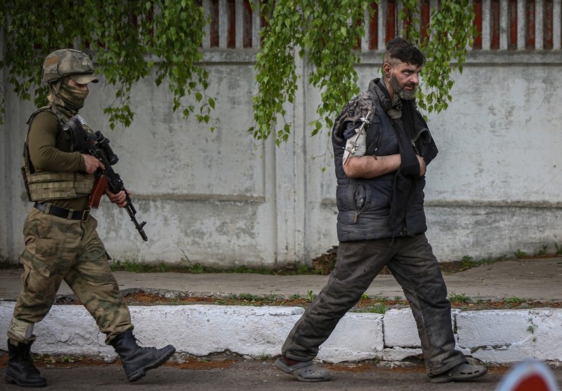 Mihailo, în momentul în care iese din uzina Azovstal, păzit de un militar din forțele armate ale autoproclamatei Republici Populare Donețk. Foto: Profimedia Images