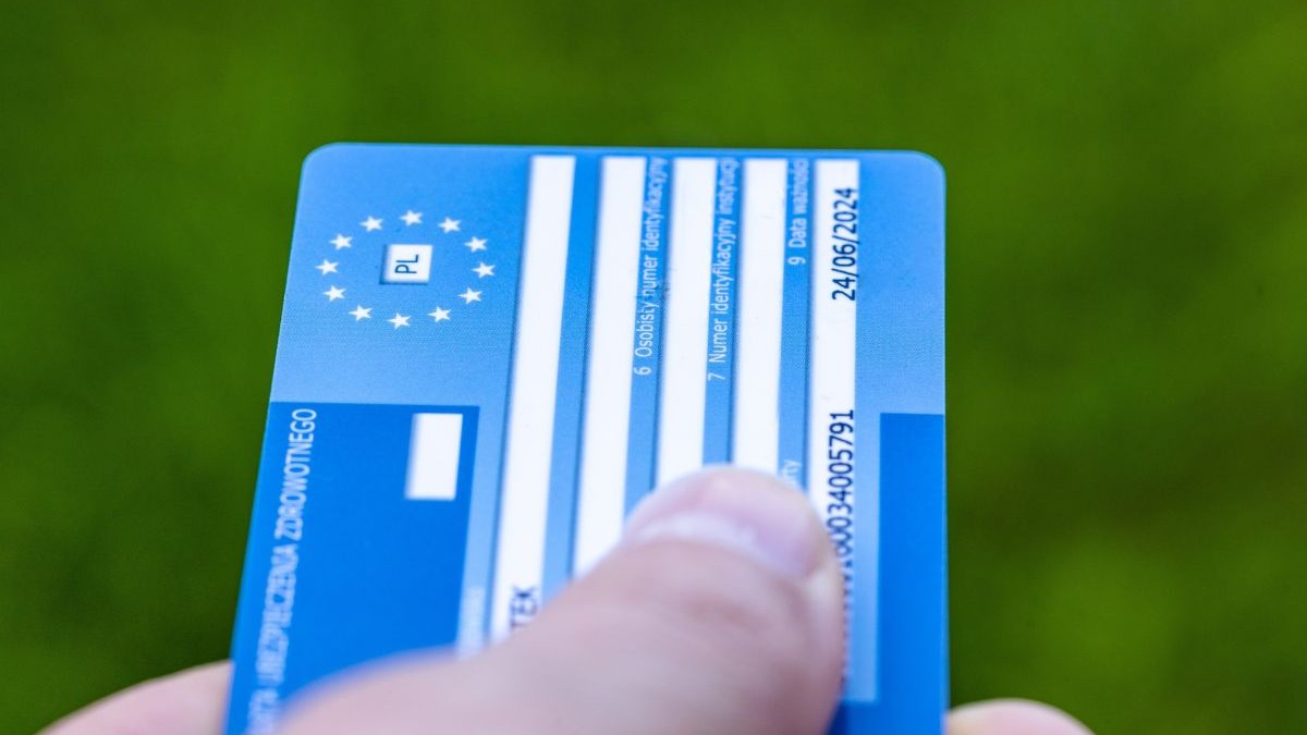 card de sanatate european, în mana unui bărbat, pe fundal verde