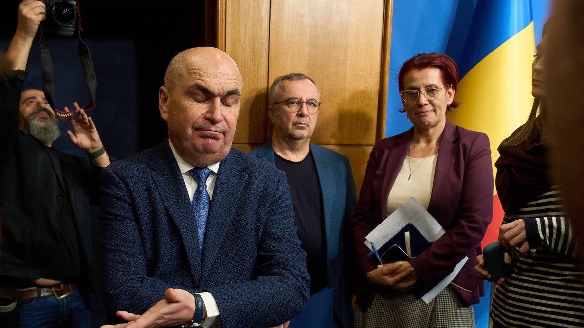 Ilie Bolojan face un gest cu mâna în timp ce pleacă de la o ședință