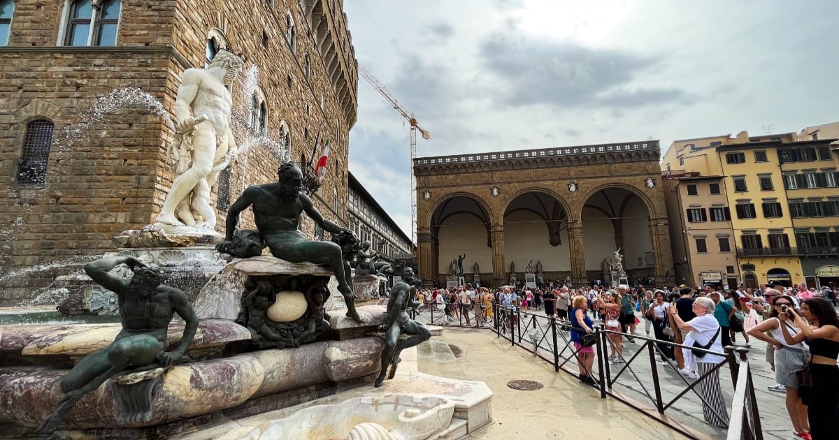 Statuia lui Neptun din Florența înconjurată de turiști care își fac poză lângă ea.
