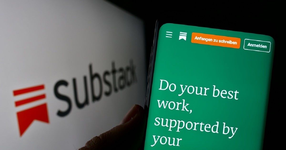 Ce este platforma Substack şi cum funcţionează - Imagine cu o persoană care ţine un smartphone în mână, lână un panou cu logo-ul Substack