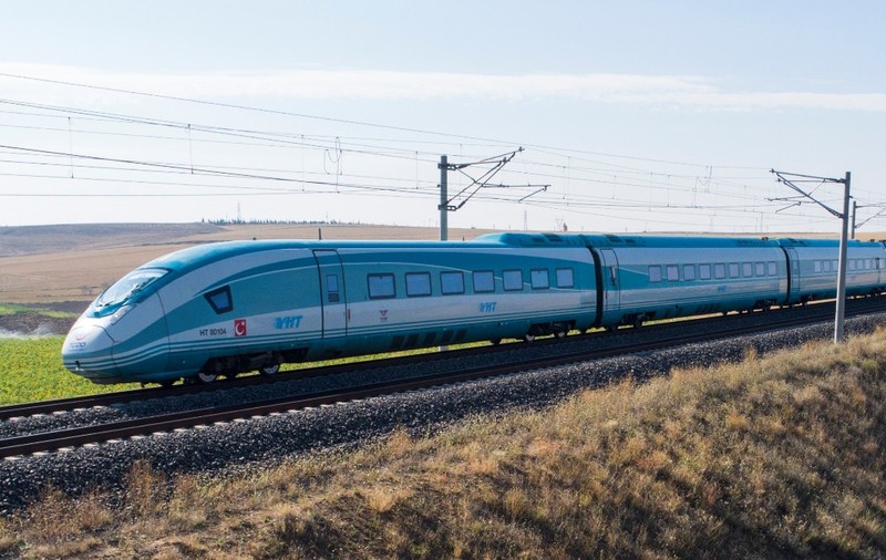 Un tren de mare viteză al căilor ferate turcești (YHT) deplasându-se pe o cale ferată prin zone rurale uscate.