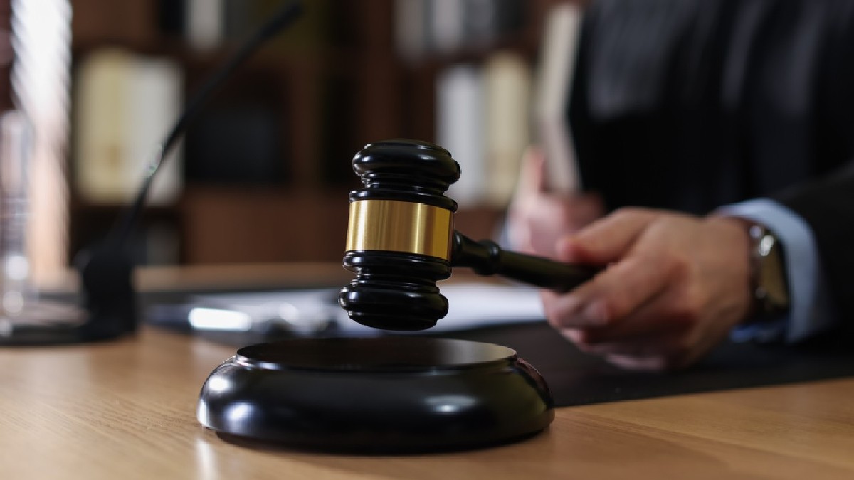 Judecător izbește cu un ciocănel în masa de lemn, într-o sală de judecată 