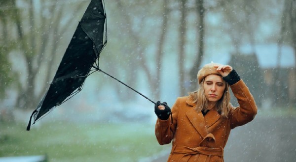 Femeie cu o umbrelă întoarsă de vânt. Persoană nefericită care suferă din cauza vremii furtunoase