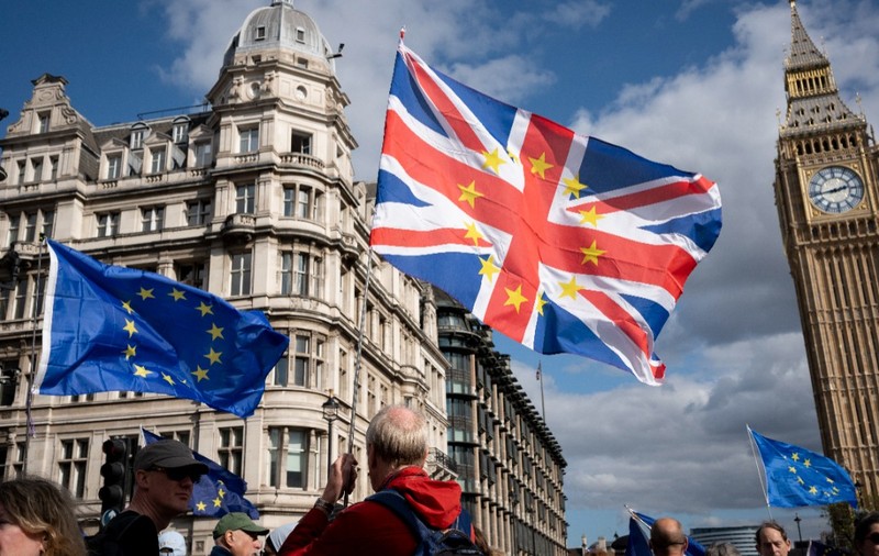 Manifestanți pro-europeni la Londra, fluturând steaguri ale Uniunii Europene și un steag combinat al Marii Britanii cu stelele UE, având turnul Big Ben pe fundal.   