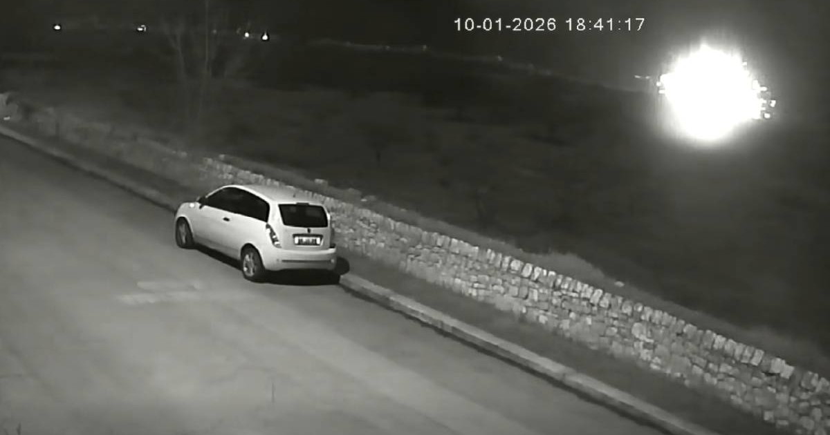Imagini de noapte de pe o camera de supraveghere, se vede o masina pe o strada, in departare o lumina puternica
