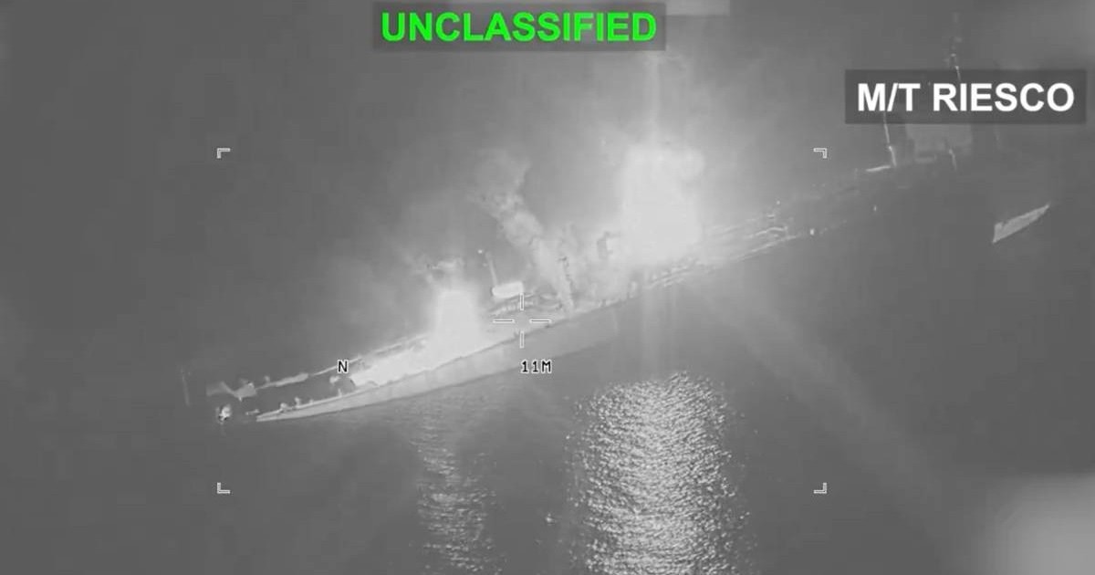 Imagine nocturnă, surprinsă în infraroșu, cu un petrolier cuprins de flăcări pe mare. Focul și fumul sunt vizibile în zona centrală a navei, iar pe cadru apar marcajele „UNCLASSIFIED” și „M/T RIESCO”.