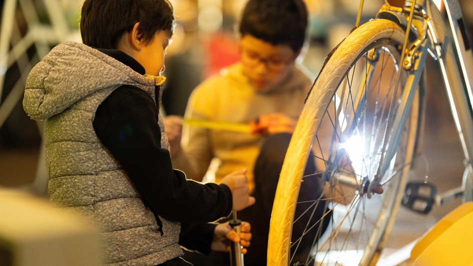 Doi băieți învață să repare o bicicletă