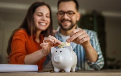 Doi soți în timp ce fac economii și pun banii într-o pușculiță
