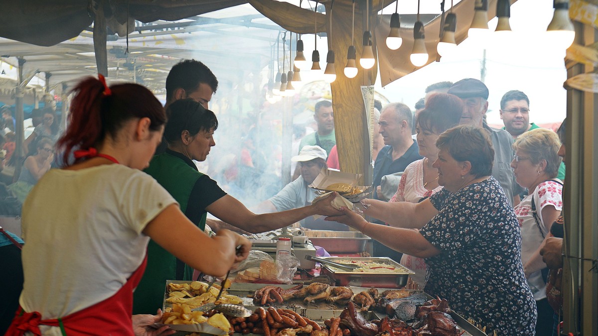 Festivalul Cârnaților de Pleșcoi, anulat din cauza referendumului pentru familie. Oameni care se înghesuie la cârnați, într-un târg din Oltenia