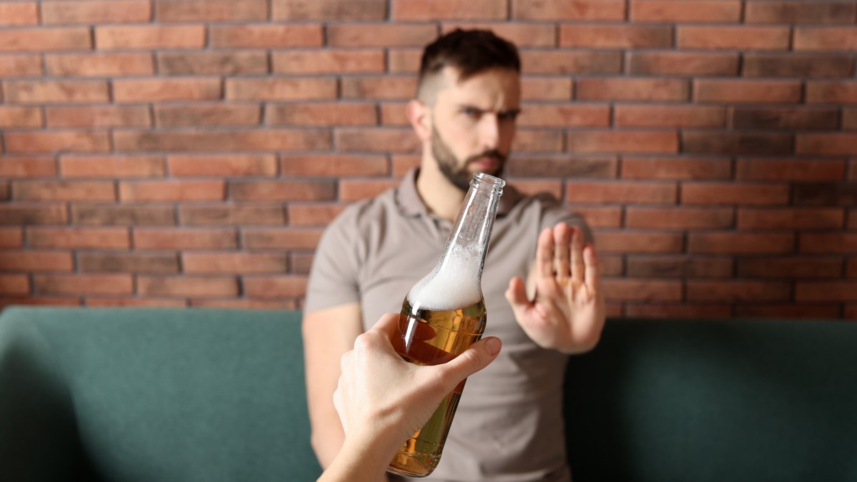 Ce se întâmplă în corpul tău dacă renunţi la consumul de alcool - Imagine cu un bărbat care face un semn de refuz când i se oferă o sticlă cu bere.