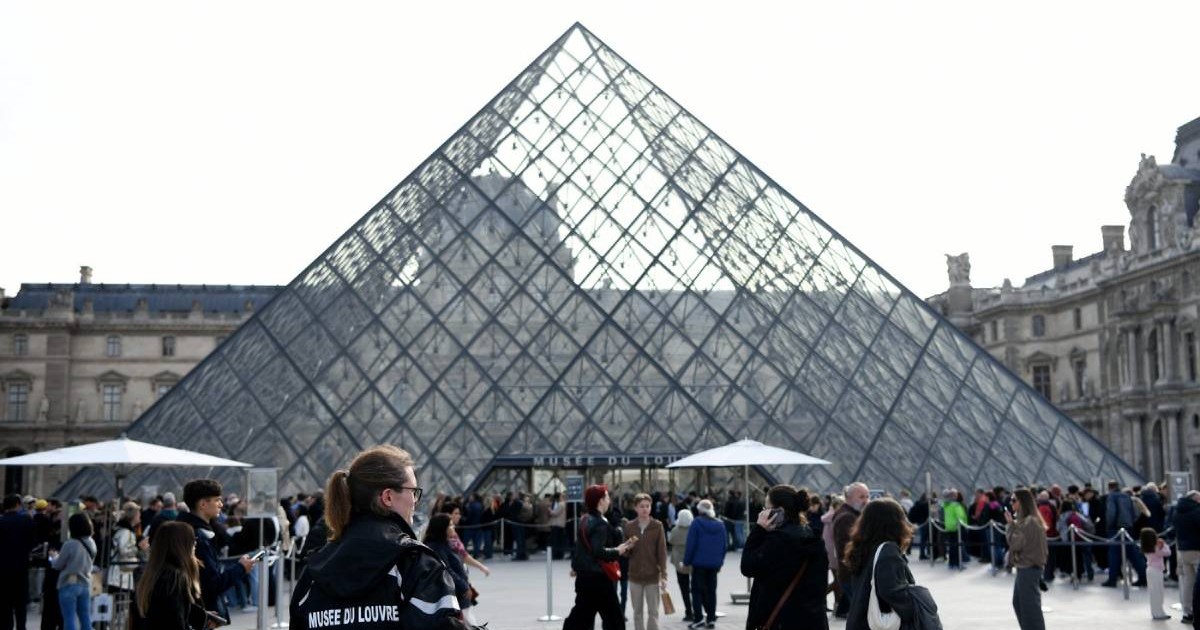 Polițiștii și turiști stând în fața Muzeului Luvru din Paris, oamenii legii păzesc intrările