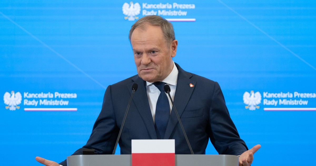 Donald Tusk, vorbind in fata unui pupitru cu steagul poloniei